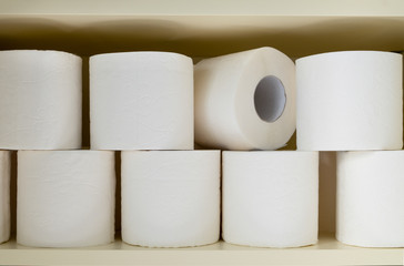Lots of rolls of white toilet paper on the shelf in the closet or pantry. Selective focus. Horizontal orientation.