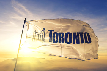 Toronto of Ontario of Canada flag waving on the top sunrise mist fog