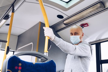 Man wearing medical mask and protective gloves in bus. Public transportation during covid-19