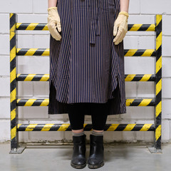 A woman is standing at the yellow-black striped protective barrier, a dead end against a brick...