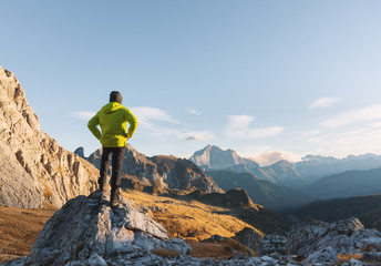 Sporty man standing on the stone against mountain valley at sunset in spring. Happy young man,...