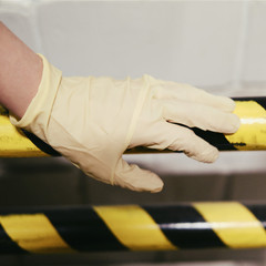 Protective yellow-black barrier and a woman hand in a medical glove. Concept of quarantine and...
