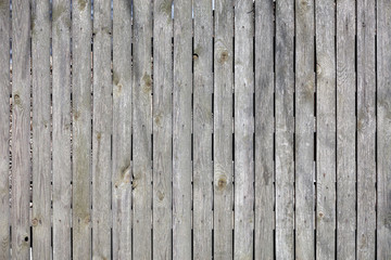 Texture and background of an old gray wooden fence with weathered wood.
