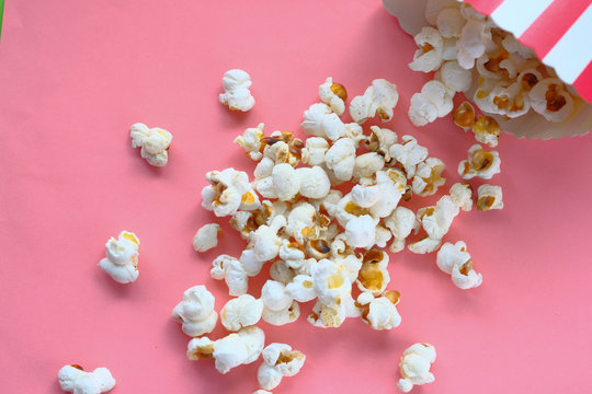 Top View Of Popcorn Spilling On Pink Background 