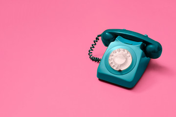 Blue vintage antique rotary phone on a pink background with copy space and room for text with a...