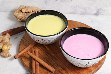 Turmeric latte and pink-golden milk for immunity, ginger and cinnamon on a gray table, helps fight viruses, has antioxidant properties, the concept of alternative medicine