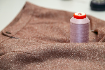 Brown fabric with purple spool of sewing thread closeup