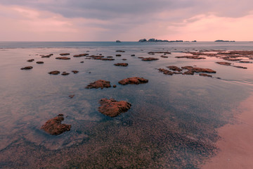Fototapeta premium Beautiful sunset seascape. Coral reef at Hikkaduwa, Sri-Lanka. Textured ocean coast with waves on long exposure.