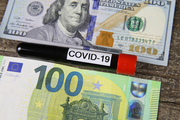 Covid-19 blood sample vial between 100 dollar us bank note and euro paper money bill