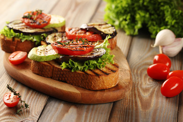 Vegetarian hot sandwich made from grilled bread, grilled eggplant, zucchini and tomatoes, with green lettuce and seasoned with olive oil and Provencal herbs. Decorated with a sprig of thyme.