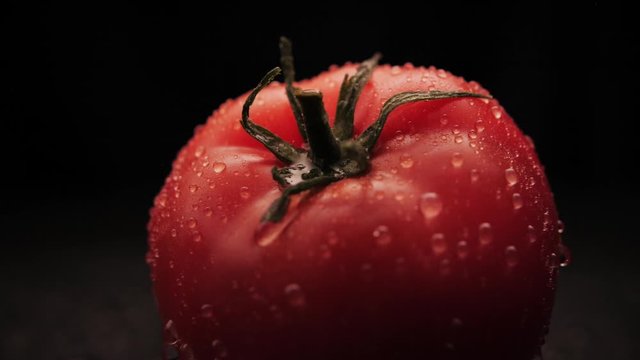 Fresh washed organic red tomato water drops on a black background. Close-up of a drop of water flows over the surface of the vegetables.Healthy eating
