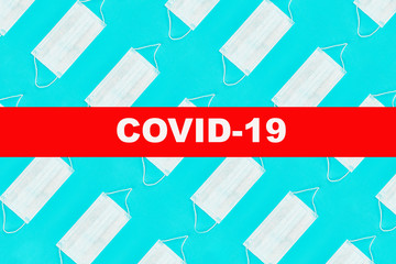 Pattern of face medical masks on blue background with text covid-19. Protection from coronavirus. Top view. Flat lay.