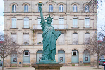 Obraz premium Small copy of the statue of liberty in front of the building