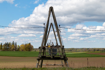 Power transformer installations in tree poles at the edge of the field overlooking the meadow