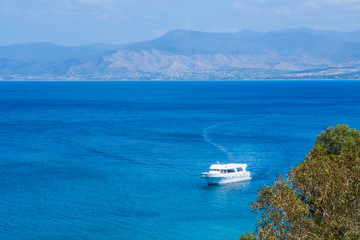 Summer seascape on Cypus. View to the bay with green grove in front and blue clouded sky. View from the hill.