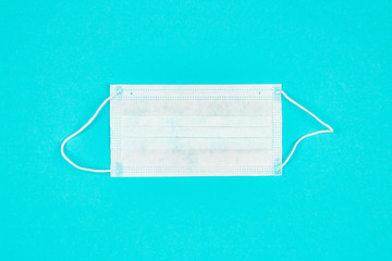A close up of medical mask on blue background. Coronavirus protection. Copy paste for text. Top view. Flat lay.