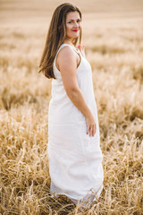 Fototapeta na wymiar beautiful girl with brunette hair on a wheat field background. warm summer time. 