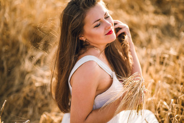 beautiful girl with brunette hair on a wheat field background. warm summer time. 