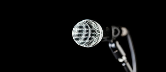 Closeup microphone. Vocal audio mic on a bleck background. Audio equipment. Karaoke concert, sing sound. Microphone, mic, karaoke, concert, voice music. Copy space - obrazy, fototapety, plakaty