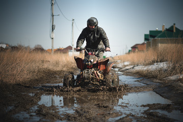 Biker riding quad bike on dirty countryside road.
