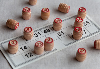 Lotto game-wooden barrels with numbers are on the playing field. Hobbies and recreation, activities while at home and in quarantine. Selective focus. Сloseup.