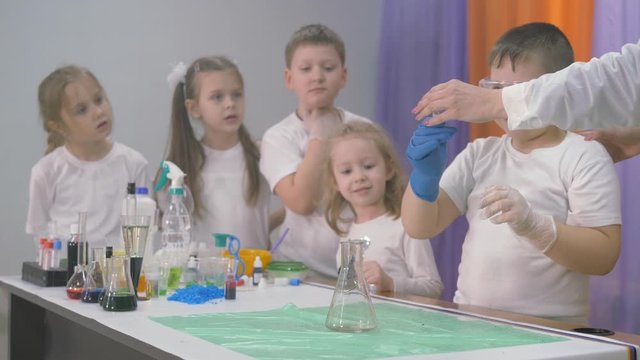 Chemical experiments for children. A woman adds ingredients to a flask for chemical experiments. A column of smoke rises from the beaker . Bright emotions of children and adults, surprise, admiration