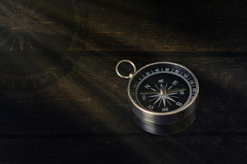 compass on a dark wooden background with rays of light