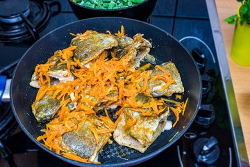 Fry the fish in the pan. Cooking at home. Diet fish with vegetables