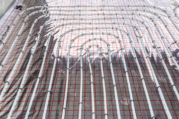 White pipes of underfloor heating systems, distributed in an individual family house on insulating foil.