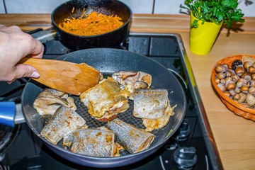 Fry the fish in the pan. Cooking at home. Diet fish with vegetables