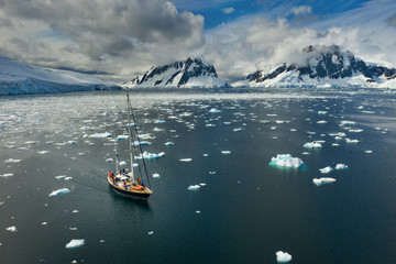 sail yacht under clouds floats in strait in Antarctica