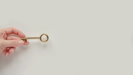 Woman hand holding gold key on white background with copyspace. Stock photo.