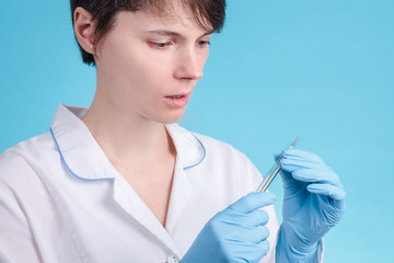 portrait of a young woman doctor on a blue background who looks at the thermometer and worries. high temperature from the virus