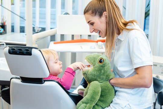 Little child in dentists surgery learning how to brush teeth