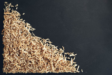 Wood shavings on black background. Background of fresh wood shavings. Copy, empty space for text