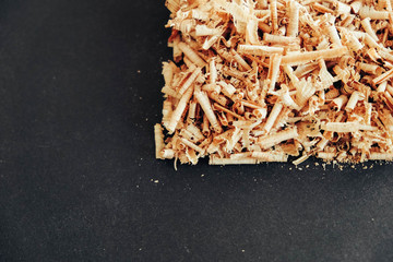 Wood shavings on black background. Background of fresh wood shavings. Copy, empty space for text