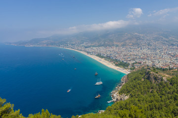 Fototapeta na wymiar Alanya. Turkey. The city beach in Alanya. The coastline is receding into the distance. The view from the bird's eye view. Alanya - a popular holiday destination for European tourists.