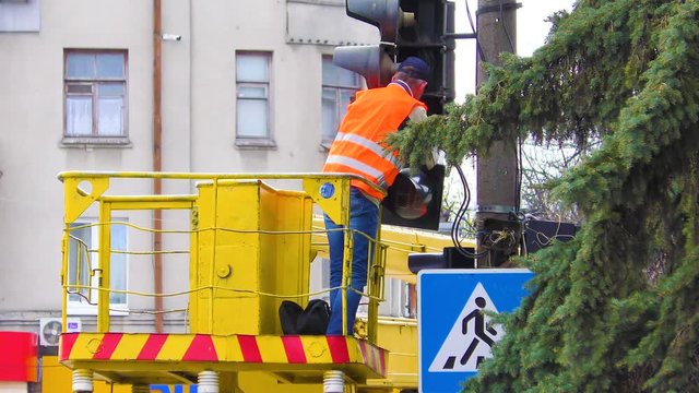 Electrical workers are busy repairing a broken traffic light on a busy intersection. Traffic light repairman worker