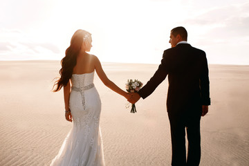 Bride and groom in the desert holding a wedding bouquet in their hands