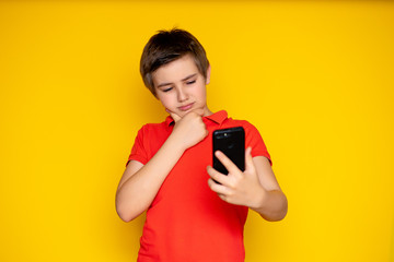 Portrait of a pretty teenager 11-12 years old with a mobile phone on a yellow background