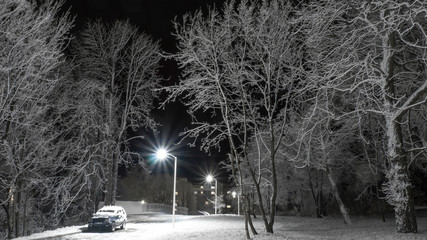 Snow-covered alley with car and lanterns at night