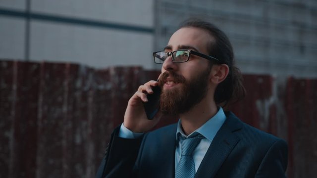 Long haired businessman make a phone call. He's got ideas from his assistant, and he says everything's fine.