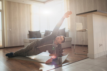 Young ordinary man go in for sport at home. Persistant freshman workout beginner stand in side...