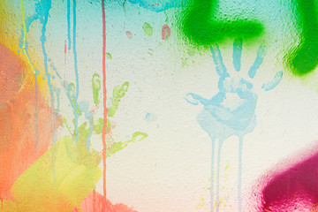 White plastered wall with colorful drips, flows and paint sprays. Handprints on white wall background