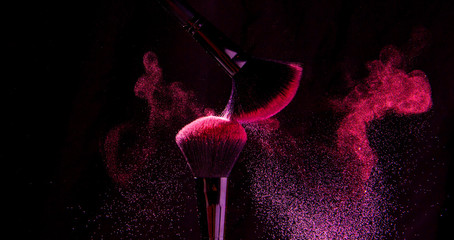 Colorful explosion on makeup brushes on a black background
