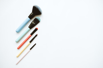 Makeup brushes of different colors isolated on a white background with copy space