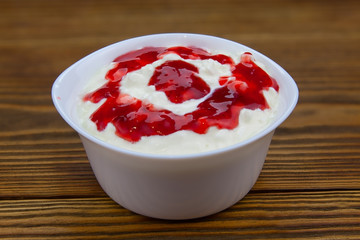 Tasty fresh grained cottage cheese on a plate on  wooden table