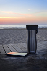 stylish cup with phone on wooden desk