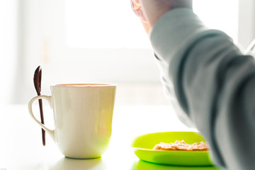 Person having lunch with a cup of coffee and a green plate