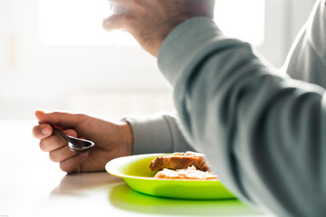 Person having lunch eating toast on a green plate and drinking a cup of coffee .